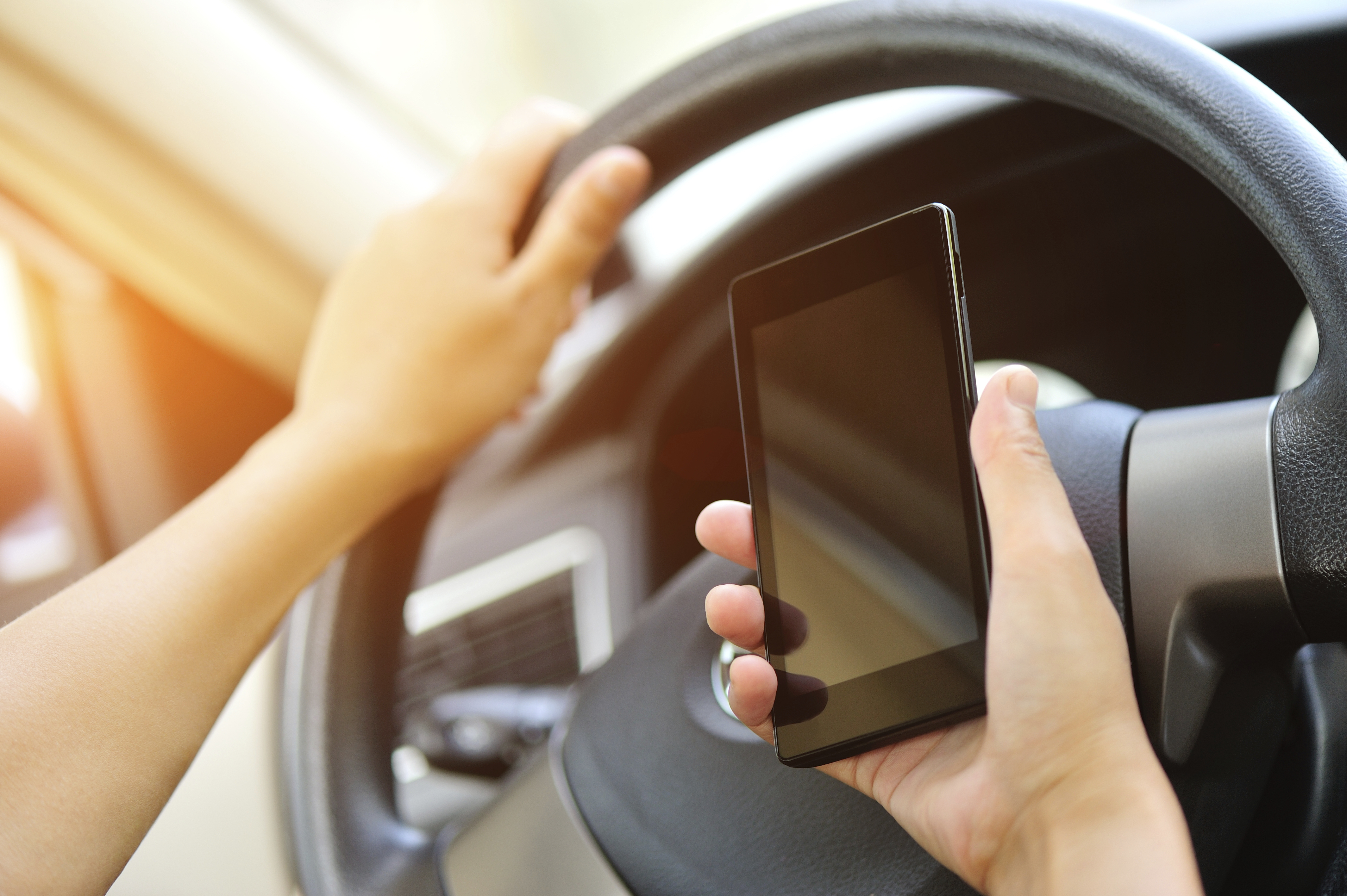 lady holding mobile phone near steering wheel