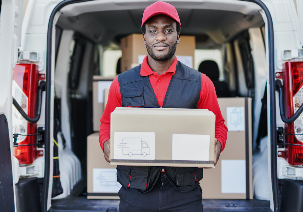 delivery driver in red cap carrying a box