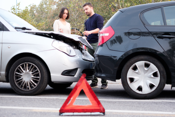 two people assessing car damage after an accident